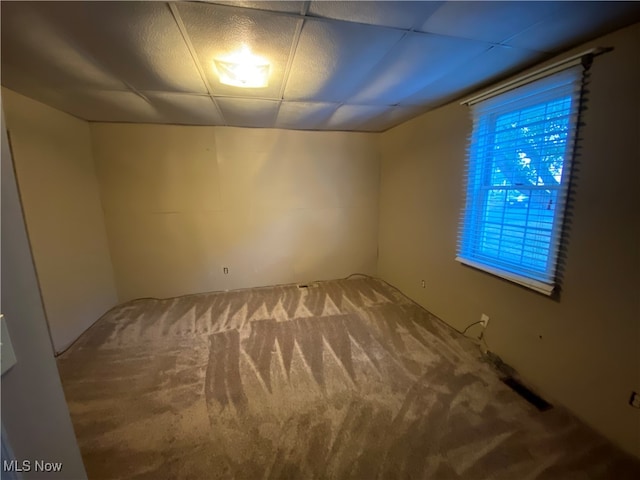 spare room featuring a paneled ceiling and carpet