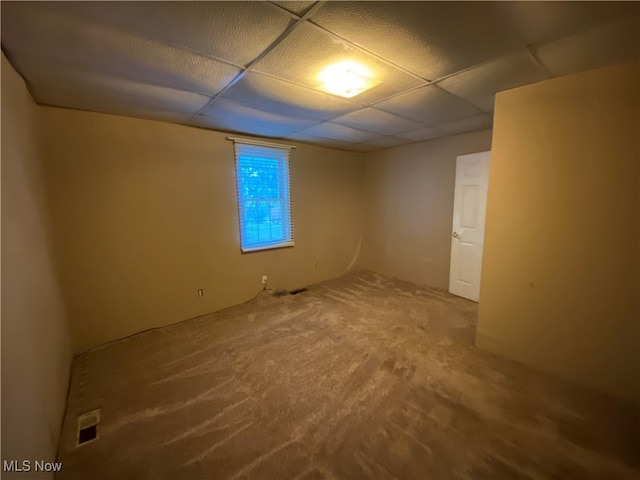 spare room featuring carpet and a drop ceiling