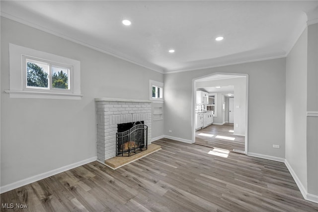 unfurnished living room with a fireplace, ornamental molding, and light hardwood / wood-style flooring