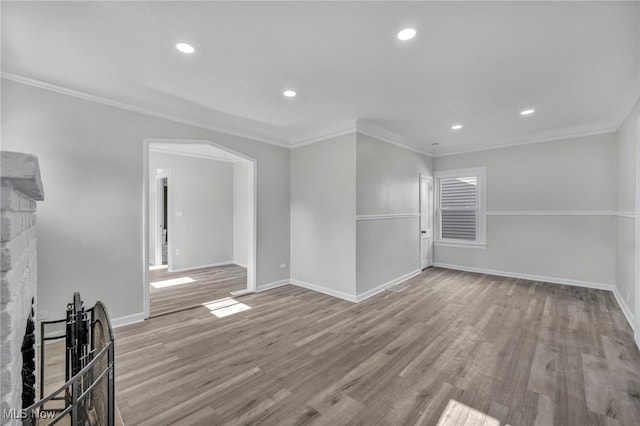 unfurnished living room with light hardwood / wood-style floors, crown molding, and a stone fireplace