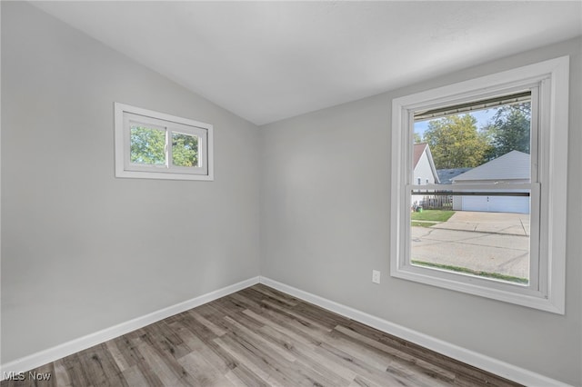 empty room with a wealth of natural light, lofted ceiling, and light wood-type flooring