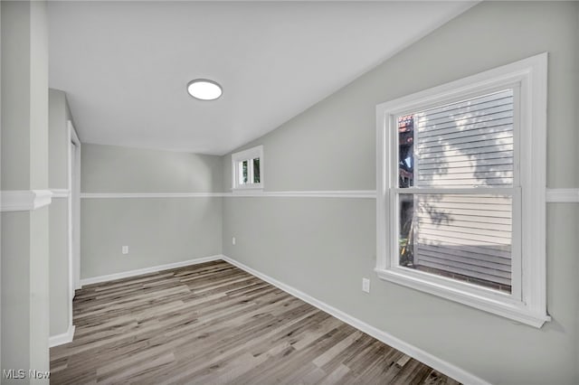 empty room with light wood-type flooring and lofted ceiling