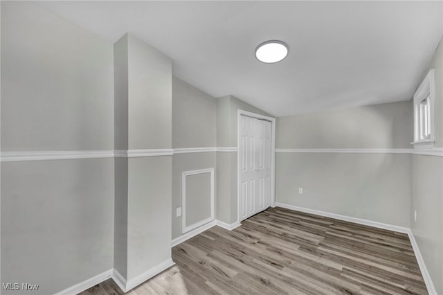 empty room featuring vaulted ceiling and hardwood / wood-style flooring