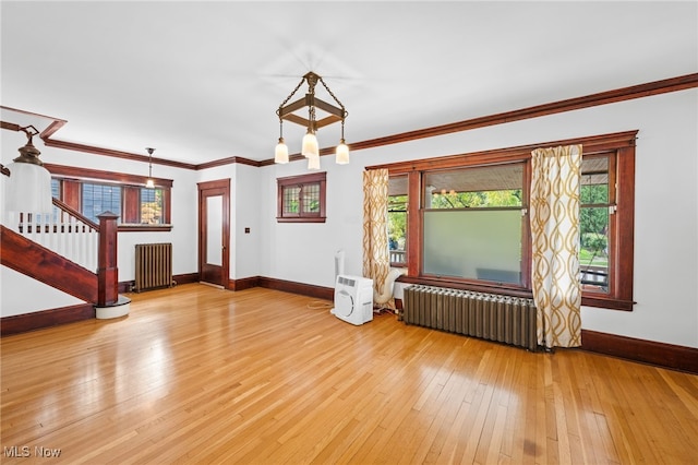 unfurnished living room with hardwood / wood-style flooring, ornamental molding, and radiator heating unit