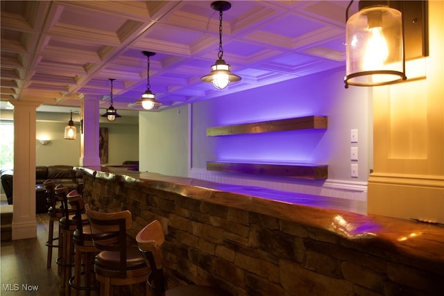 bar featuring hanging light fixtures, hardwood / wood-style flooring, ornamental molding, ornate columns, and coffered ceiling