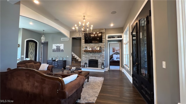 living room with a stone fireplace, an inviting chandelier, and hardwood / wood-style flooring