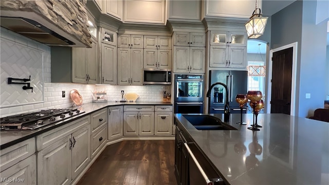 kitchen with decorative backsplash, hanging light fixtures, dark hardwood / wood-style flooring, appliances with stainless steel finishes, and ventilation hood