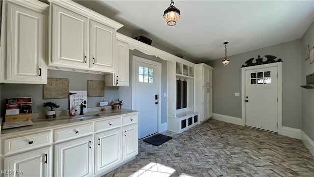 kitchen featuring white cabinetry, sink, and pendant lighting