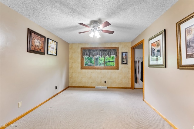 carpeted empty room featuring a textured ceiling and ceiling fan