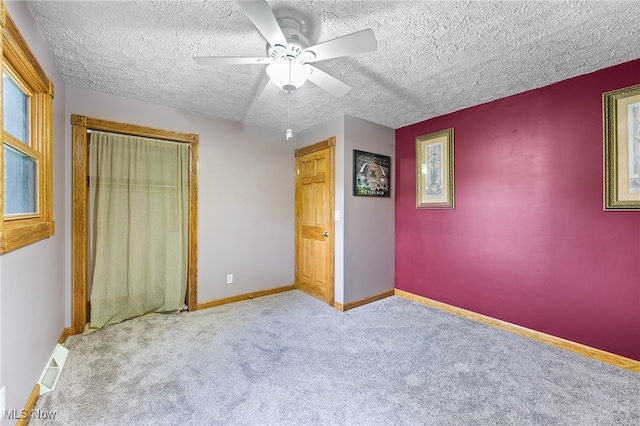 unfurnished bedroom featuring ceiling fan, a textured ceiling, light carpet, and a closet