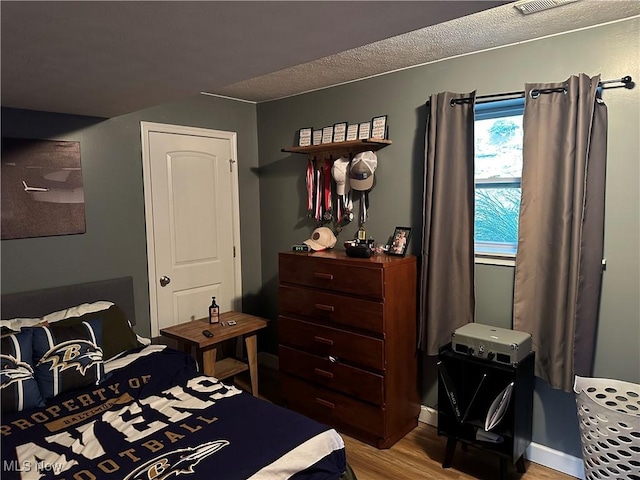 bedroom featuring a textured ceiling and light hardwood / wood-style floors