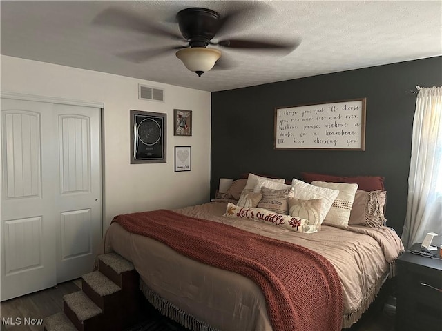 bedroom featuring hardwood / wood-style floors, a textured ceiling, a closet, and ceiling fan