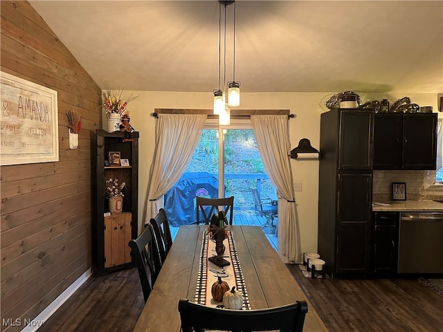 dining room with dark hardwood / wood-style flooring, wooden walls, and vaulted ceiling