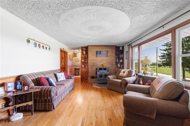 living room with a wood stove, a textured ceiling, and light wood-type flooring