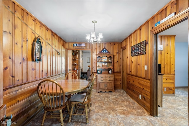 dining space featuring wood walls and an inviting chandelier