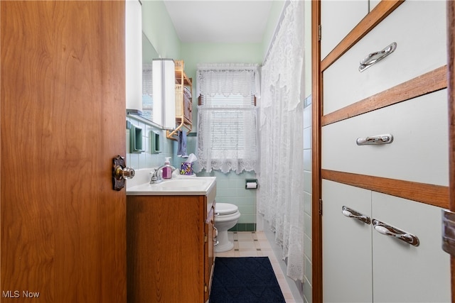 bathroom with tile walls, tile patterned flooring, a shower with shower curtain, vanity, and toilet