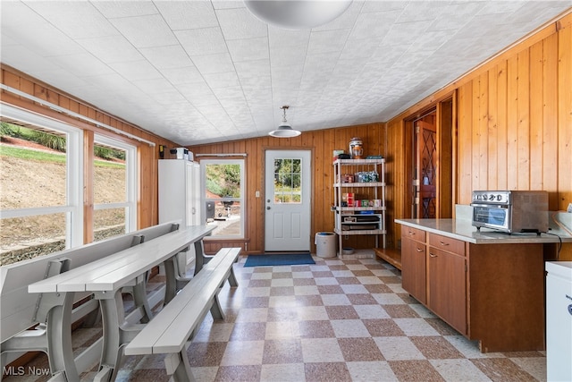 kitchen featuring decorative light fixtures, wooden walls, and vaulted ceiling