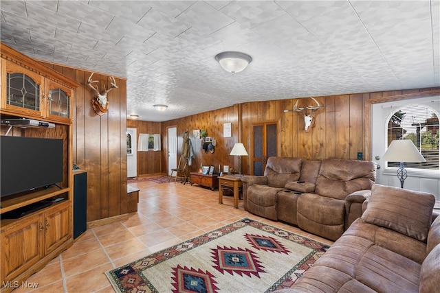 living room with a textured ceiling, wooden walls, and light tile patterned floors