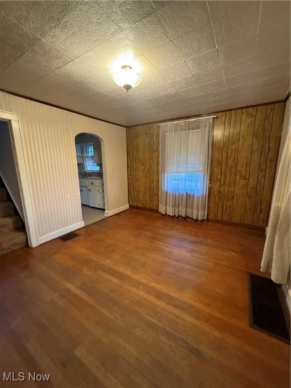 interior space featuring connected bathroom, wood walls, and dark wood-type flooring