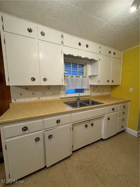 kitchen featuring decorative backsplash, white cabinetry, and sink