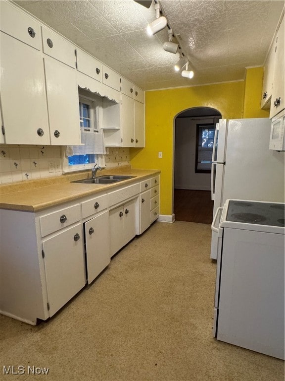 kitchen featuring decorative backsplash, white appliances, white cabinetry, and sink