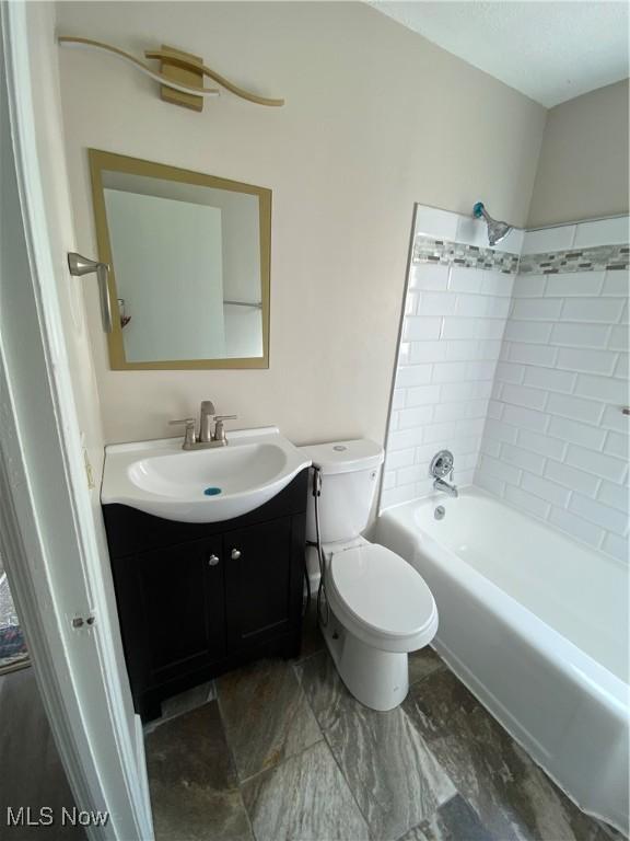 full bathroom with vanity, tiled shower / bath combo, and toilet