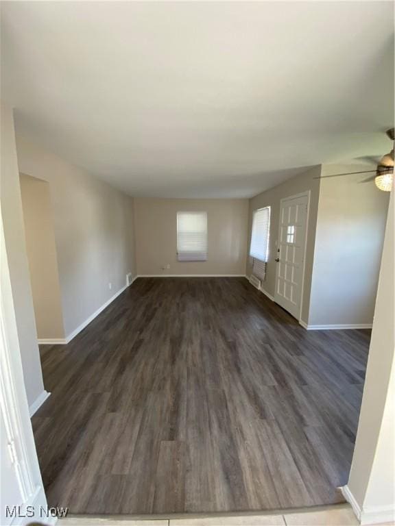 unfurnished living room with dark hardwood / wood-style flooring and ceiling fan