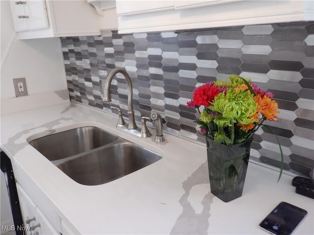 details featuring tasteful backsplash, sink, and white cabinets