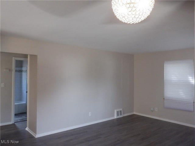 spare room featuring dark hardwood / wood-style flooring and a notable chandelier