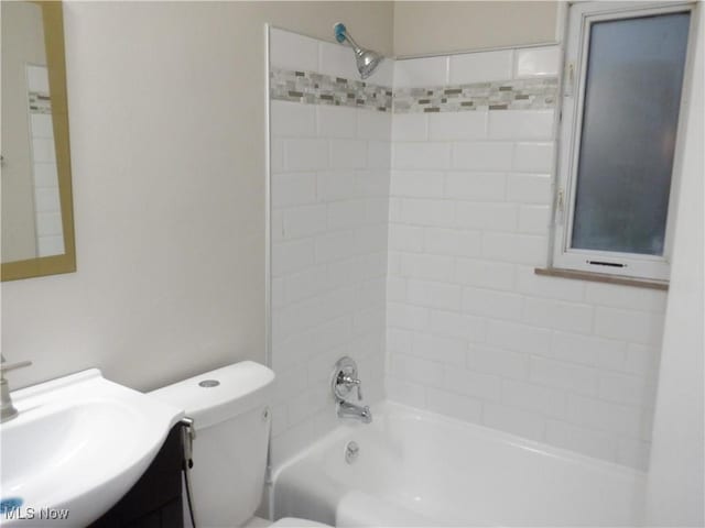 full bathroom featuring vanity, tiled shower / bath combo, and toilet