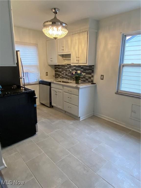 kitchen featuring decorative backsplash, appliances with stainless steel finishes, sink, white cabinets, and light tile patterned flooring