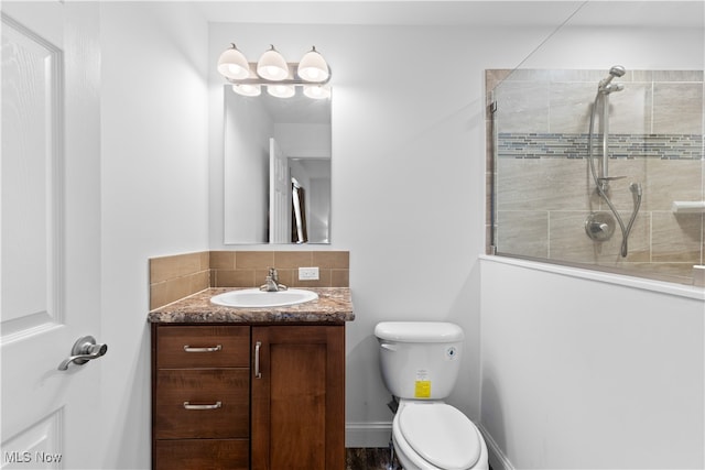 bathroom featuring a tile shower, vanity, and toilet