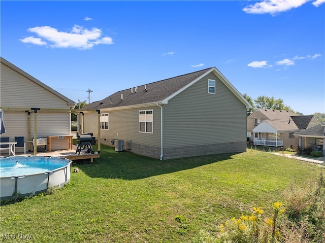 rear view of house featuring central AC unit and a yard