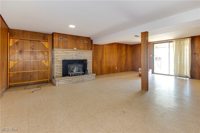 unfurnished living room with a brick fireplace and wood walls