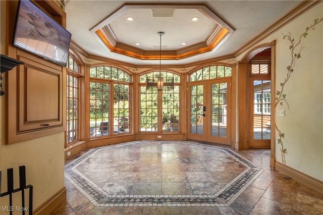 unfurnished dining area featuring french doors, a raised ceiling, ornamental molding, and a healthy amount of sunlight