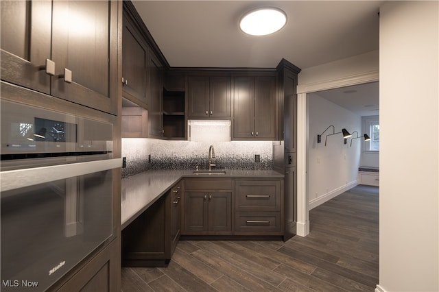 kitchen with dark brown cabinetry, sink, tasteful backsplash, oven, and dark hardwood / wood-style floors