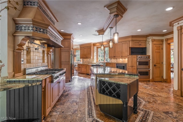 kitchen featuring decorative backsplash, decorative light fixtures, light stone countertops, and a kitchen island