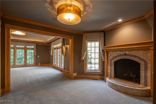 unfurnished living room featuring carpet floors, a tiled fireplace, and ornamental molding