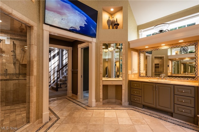 bathroom with a towering ceiling, tile patterned flooring, walk in shower, and vanity