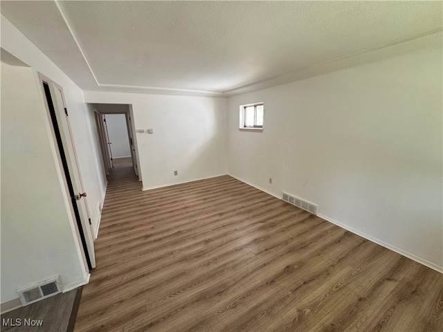 unfurnished room featuring a textured ceiling and dark hardwood / wood-style floors