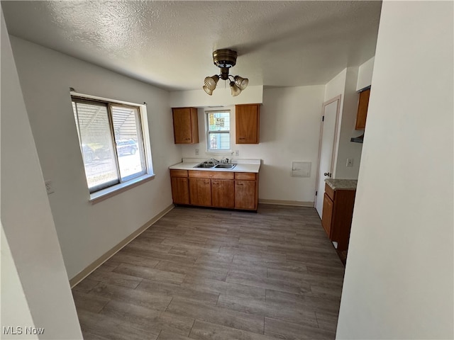 kitchen with a textured ceiling, light wood-type flooring, and sink