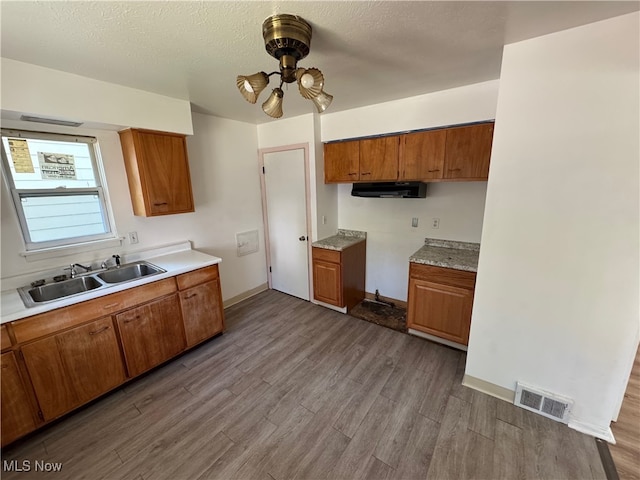 kitchen with a textured ceiling, hardwood / wood-style flooring, ceiling fan, and sink