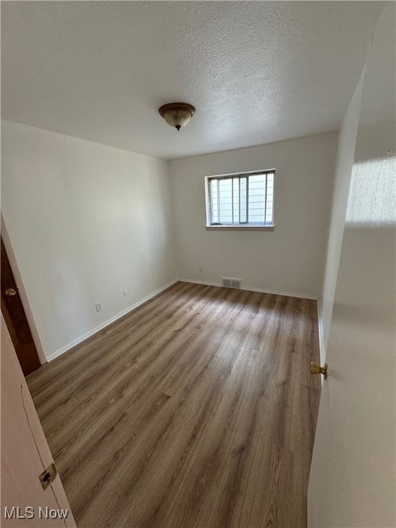 empty room featuring a textured ceiling and dark wood-type flooring