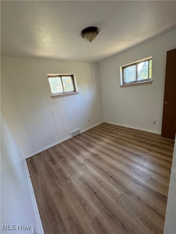 unfurnished room with light wood-type flooring and a textured ceiling