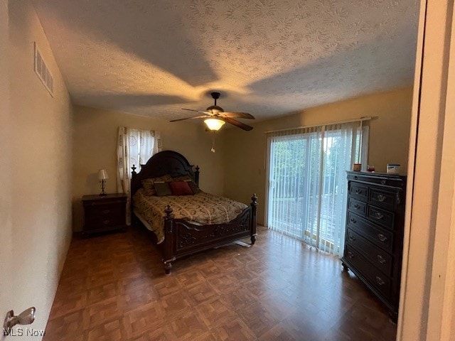 bedroom featuring ceiling fan, a textured ceiling, dark parquet flooring, and access to exterior