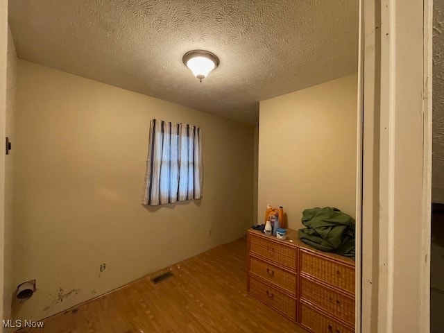 unfurnished room featuring wood-type flooring and a textured ceiling