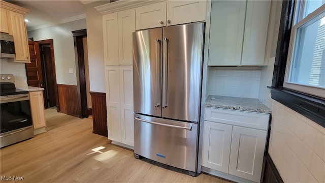 kitchen featuring white cabinets, ornamental molding, stainless steel appliances, light stone countertops, and light hardwood / wood-style floors