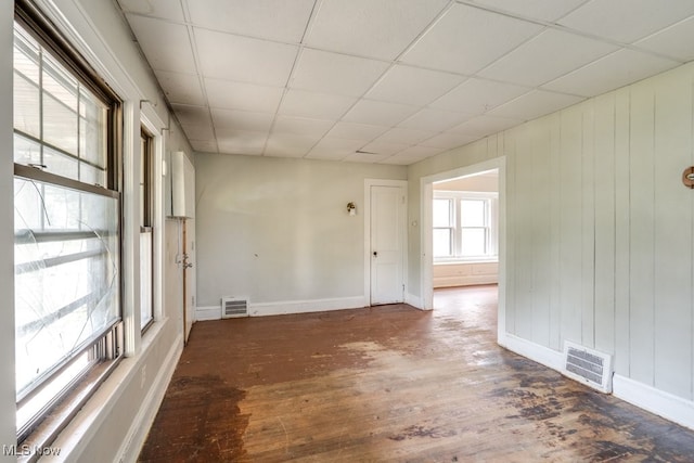 spare room with a paneled ceiling and dark hardwood / wood-style flooring