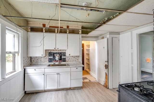 kitchen featuring light wood-type flooring, white cabinetry, tasteful backsplash, and sink