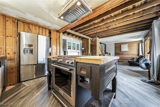 kitchen with a center island, wood counters, dark wood-type flooring, wooden walls, and appliances with stainless steel finishes